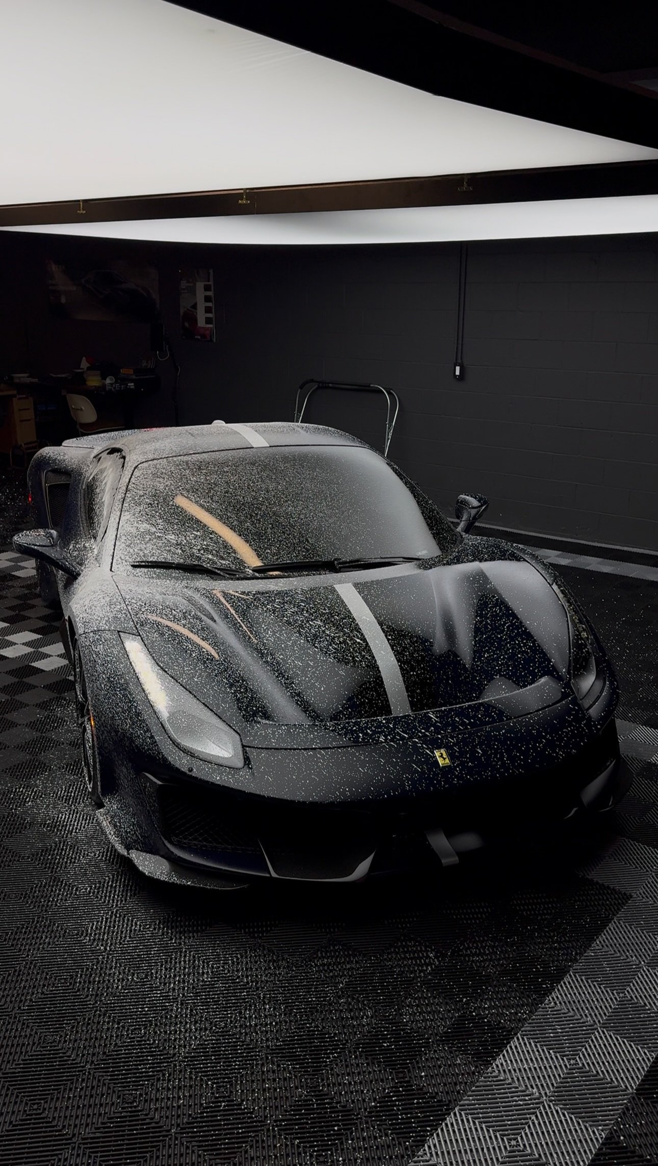 Black sports car covered in water droplets in dark showroom