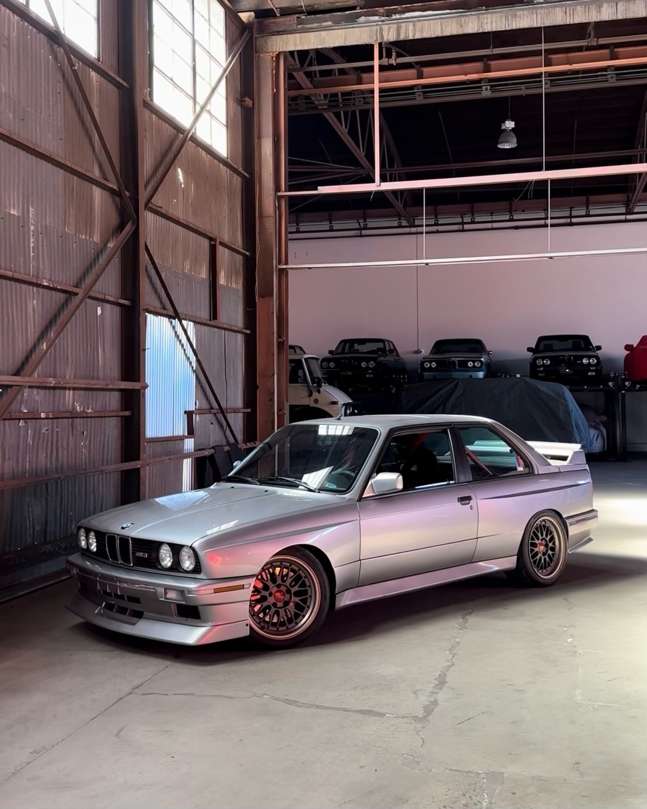 Silver BMW sports coupe with bronze wheels parked in an industrial warehouse