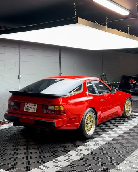 Red Lancia Delta Integrale sports car parked in modern garage with LED lighting and checkered flooring