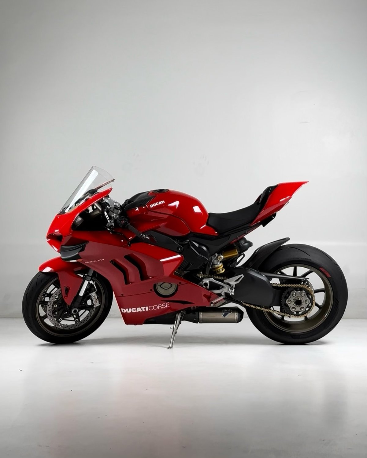 Red Ducati Corse sport motorcycle with black accents shown in profile view against a white background