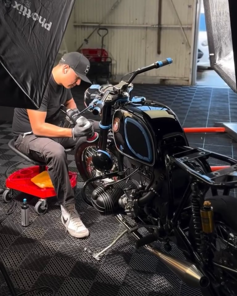 Mechanic working on a black motorcycle with red accents in a garage workshop setting